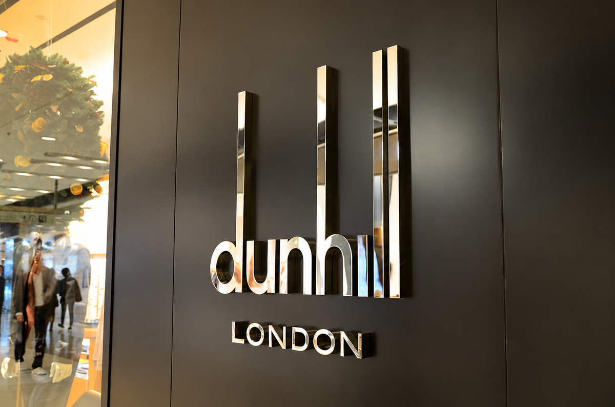 Silver mirror-finished logo letters installed on a dark interior wall
